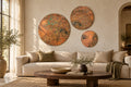 Copper Orbit Mystic Copper Nebula – set of 3 round real copper wall panels, warm copper with charcoal clouds and turquoise verdigris, above a beige sofa in a sunlit living room, room visualization